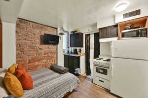 Interior space with white appliances, dark brown cabinets, and light hardwood / wood-style floors