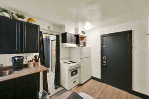 Kitchen with light hardwood / wood-style flooring, sink, and white appliances