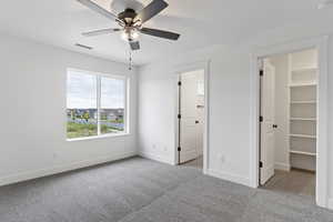 Unfurnished bedroom featuring light carpet, a walk in closet, ceiling fan, and a closet