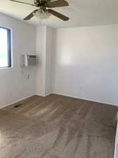 Carpeted bedroom with a wall mounted AC and ceiling fan