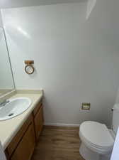 1/2 Bathroom featuring toilet, hardwood / wood-style flooring, and vanity