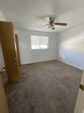 second bedroom featuring ceiling fan and dark colored carpet and window blinds