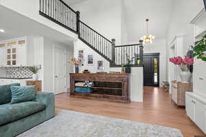 Living room featuring light wood-type flooring, high vaulted ceiling, and an inviting chandelier