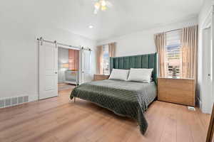 Master Bedroom featuring multiple windows, a barn door, and light hardwood / wood-style floors