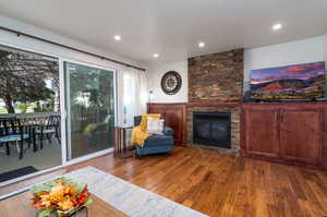 Living area with hardwood / wood-style floors and a stone fireplace