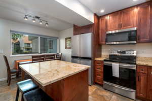 Kitchen with a center island, stainless steel appliances, and light stone counters