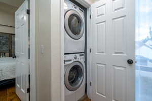 Clothes washing area featuring dark hardwood / wood-style floors and stacked washer / dryer