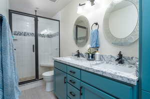 Bathroom featuring vanity, toilet, a shower with shower door, and tile patterned flooring