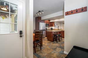 Interior space with a kitchen island, stainless steel appliances, a kitchen breakfast bar, and rail lighting