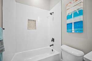 Bathroom with toilet and tiled shower / bath combo