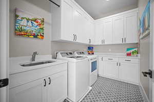 Laundry area featuring cabinets, sink, and independent washer and dryer