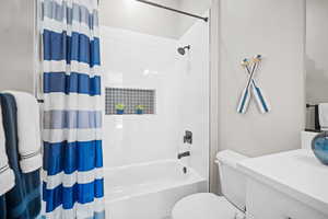 Full bathroom with vanity, toilet, and shower / bathtub combination with curtain