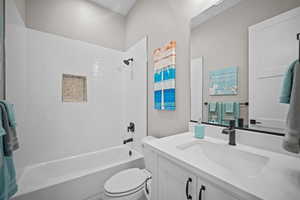 Full bathroom with tiled shower / bath, vanity, and toilet