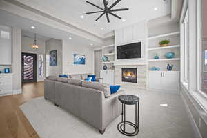 Living room with light hardwood / wood-style flooring, ceiling fan, and a fireplace