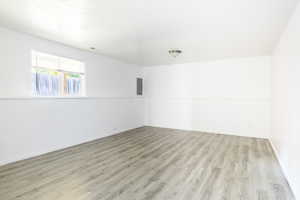 Empty room featuring electric panel and light hardwood / wood-style floors