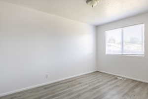 Unfurnished room with hardwood / wood-style flooring and a textured ceiling