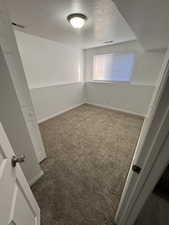 Carpeted spare room with a textured ceiling