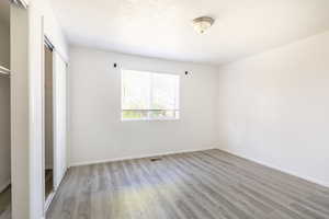 Unfurnished bedroom featuring a textured ceiling, a closet, and light hardwood / wood-style floors