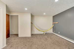 Interior space featuring a textured ceiling, light colored carpet, and baseboard heating