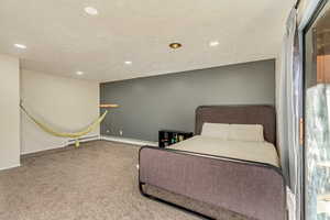 Bedroom with baseboard heating, carpet floors, and a textured ceiling