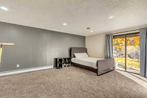 Unfurnished bedroom with carpet flooring, access to exterior, a textured ceiling, and baseboard heating