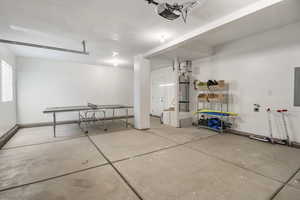 Garage featuring electric panel, strapped water heater, and a garage door opener