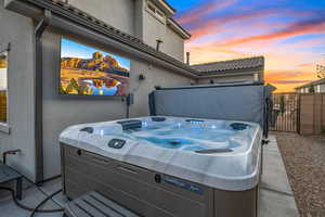 Patio terrace at dusk featuring a hot tub