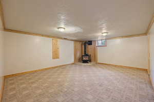 Basement featuring a wood stove, and light colored carpet