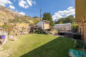 View of yard with central AC unit, a storage shed, and a deck with mountain view