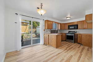 Kitchen with sink, light hardwood / wood-style floors, kitchen peninsula, and stainless steel range oven