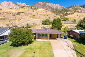 View of front of home featuring a carport, a front lawn, and a mountain view