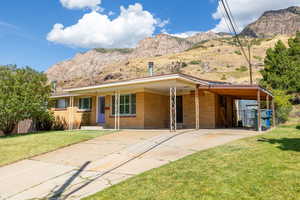 Ranch-style home featuring a mountain view, a front lawn, and a carport