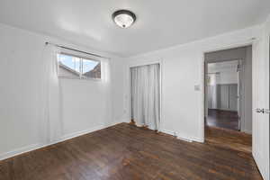 Bedroom room featuring light walls and dark hardwood flooring, and a walk-in closet