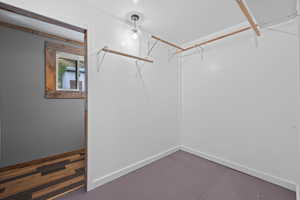 Spacious primary bedroom closet with painted hardwood flooring