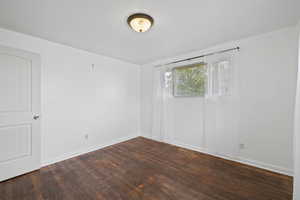 Bedroom room featuring light walls and dark hardwood flooring