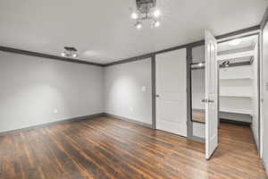 Bonus room with dark wood-type flooring, and a walk in closet