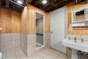 Bathroom featuring a shower, tile walls, wooden walls, and tile patterned floors