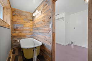 Bathroom featuring a bathing tub, wood walls, and hardwood / wood-style floors