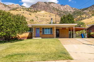 View of front of property with a mountain view, a carport, and a front yard