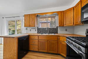 Kitchen with black appliances, light LVP floors, sink, and kitchen peninsula