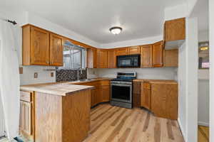 Kitchen with light wood-type flooring, stainless steel range oven, butcher block counters, and sink