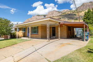 Rear view of house featuring a lawn, a mountain view, covered porch, and a carport