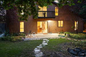 Back of house featuring a balcony, a patio area, and a yard