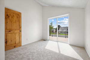 Carpeted empty room with vaulted ceiling and a textured ceiling