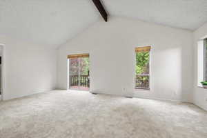 Carpeted spare room with beamed ceiling, high vaulted ceiling, and a textured ceiling