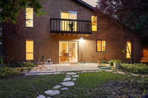 Rear view of house with a lawn, a patio area, and a balcony