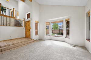 Interior space with a textured ceiling, high vaulted ceiling, and light colored carpet