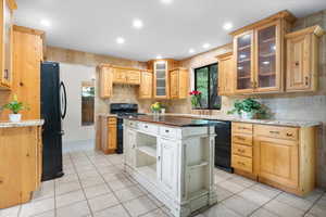 Kitchen with black appliances, light brown cabinetry, and light tile patterned floors