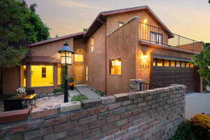 View of front facade featuring a balcony, a garage, and a patio