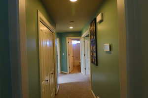 Hallway featuring light colored carpet